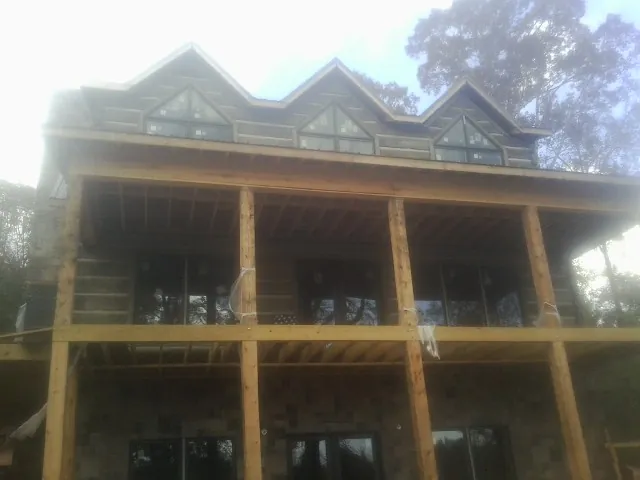 Dormers and porch framing on a large log home under construction — Roof Coating work by our crew in Alamance