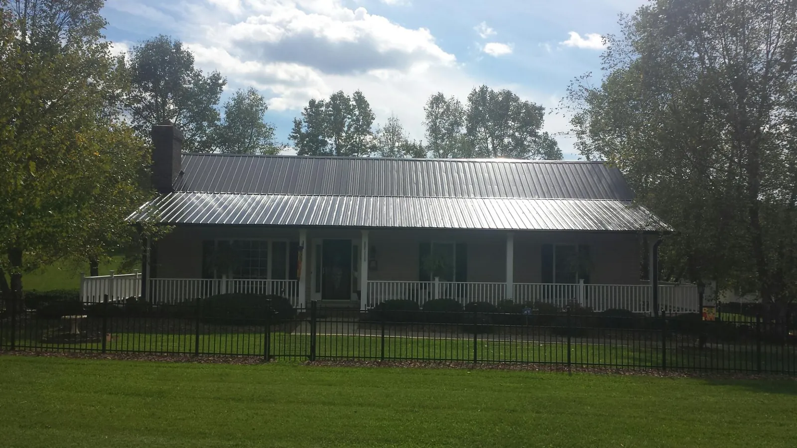 Gray metal roof on a brick ranch with a full width front porch — Gutter Guard Installation work by our crew in Alamance