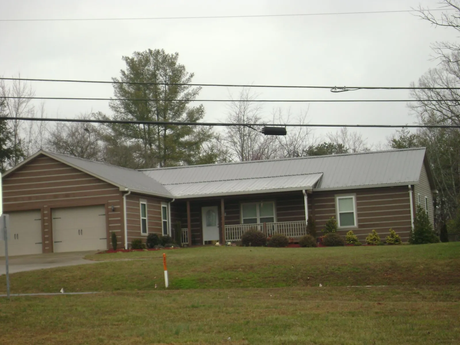 Gray metal roof on a log sided ranch home with a front porch in Alamance
